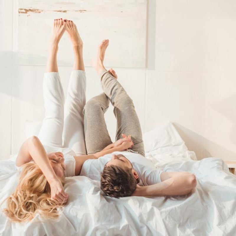 happy couple relaxing in bed and holding hands at morning